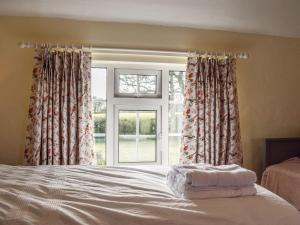 a bedroom with a bed and a large window at Hollywell Cottages in Clifton