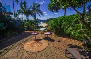 un patio con 2 sillas y una mesa con vistas al océano en WategosRent en Byron Bay