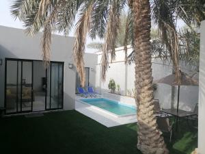 a villa with a palm tree and a swimming pool at شاليه اللويمي in Al Hofuf