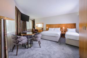 a hotel room with two beds and a table and chairs at Glashaus Hotel in Tallaght