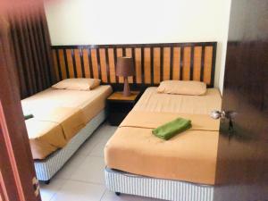 two beds in a hotel room with a green pillow at 3 room apartment with garden view in Banting