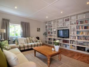 sala de estar con estanterías de libros blancos y TV en Hoogwater Farmhouse, en Wolseley
