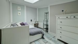 a white bedroom with a bed and a dresser at Urban Nest Apartments Bon 5 in Krakow