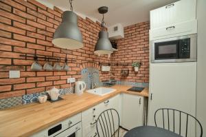 a kitchen with a white refrigerator and a brick wall at Urban Nest Apartments Bon 5 in Krakow
