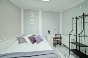 a white bedroom with a bed with purple pillows at Urban Nest Apartments Bon 5 in Krakow