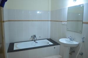 a bathroom with a sink and a tub and a mirror at Hotel City Palace in Brahmapur +20 photos