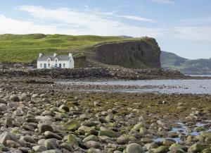 a white house on the shore of a rocky beach at Church Island View Holiday Home in Waterville