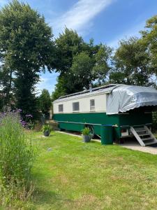 een groene en witte trailer met een zeil erop bij Bij grenspaal 243 in Essen