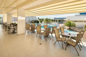 a patio with tables and chairs and a swimming pool at Hotel Olympia in Vodice
