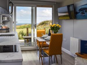 a kitchen with a table and chairs with a view of the ocean at Uk39216 - Swn Y Mor in Holyhead