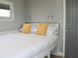 a white bed with orange and white pillows on it at Uk39216 - Swn Y Mor in Holyhead