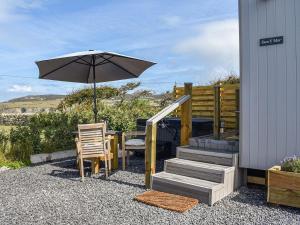 a patio with a table and an umbrella and a chair at Uk39216 - Swn Y Mor in Holyhead