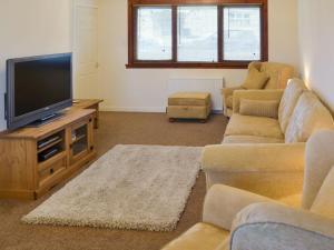 sala de estar con TV de pantalla plana y sofás en Cluaran Cottage en Tain