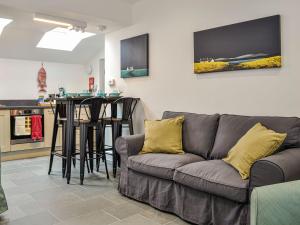 a living room with a gray couch and a kitchen at Fifie Cottage in Johnshaven