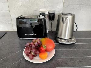 a plate of fruit on a counter next to a toaster at Bright & modern 1-bed flat in the heart of Fulham in London