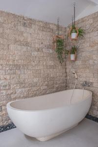 y baño con bañera y pared de ladrillo. en Villa Karma Legian, en Legian