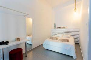 a white bedroom with a bed and a red chair at Prima Gardens City Studios in Larnaca