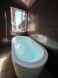 uma banheira na casa de banho com uma janela em UMIBE IseShima em Shima