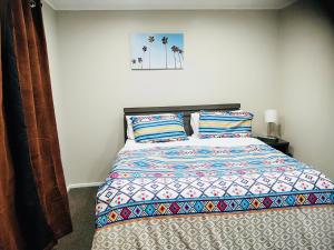 ein Schlafzimmer mit einem Bett mit einer bunten Bettdecke und Kissen in der Unterkunft Trentham Gem in Upper Hutt