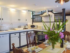 a kitchen with white cabinets and a table with purple flowers at The Coach House in Cove