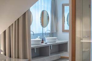 a bathroom with two sinks and two mirrors at CASPAR Swiss Quality Hotel in Muri