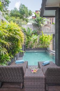una piscina con 2 sillas de mimbre y una mesa en Villa Karma Legian, en Legian