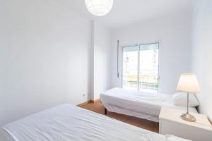a white room with two beds and a window at Rochato Dreams in Portimão