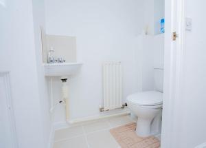 a white bathroom with a toilet and a sink at Intellect Suites in Northampton