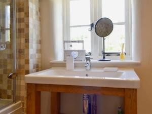 a bathroom with a sink and a window and a mirror at Periwinkle Cottage in Great Longstone