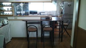 a kitchen with a table with stools and a refrigerator at ゲストハウス小富士 in Oita