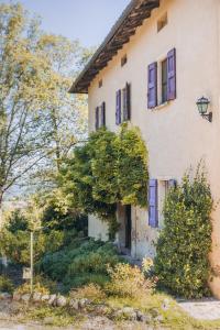 una casa antigua con ventanas azules y árboles en Agriturismo Montevecchio Isolani, en Monte San Pietro