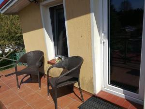 3 Stühle auf einer Veranda neben einem Fenster in der Unterkunft Pokój 2-osobowy z balkonem in Danzig