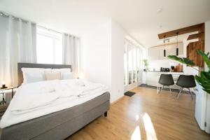 a white bedroom with a large bed and a kitchen at Studio WHITE - Central - Balcony - Fair - Kitchen in Neuss