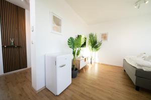 a white room with a bed and plants in it at Studio WHITE - Central - Balcony - Fair - Kitchen in Neuss