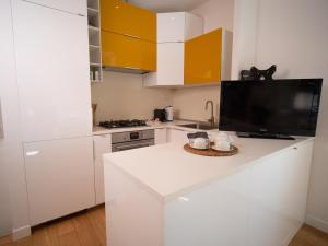 Il comprend une cuisine blanche avec des placards blancs et une télévision. dans l'établissement Olimpico deluxe apartment, à Rome