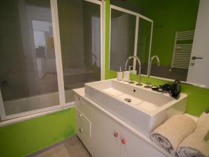 La salle de bains est pourvue d'un lavabo blanc et d'un mur vert. dans l'établissement Olimpico deluxe apartment, à Rome