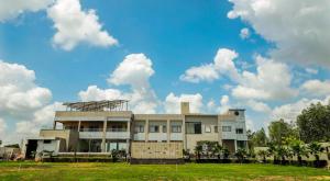 a building in a field with a cloudy sky at Hotel Amar Vilas & Resort in Bharatpur