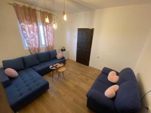 a living room with a blue couch and two chairs at Apartmani Home in Zaječar