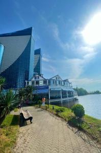 un grand bâtiment avec un banc à côté de l'eau dans l'établissement Superior Sea View Aparthotel in Orbi City Batumi, à Batoumi