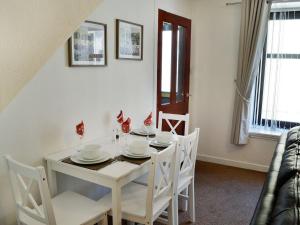 a white dining room with a white table and chairs at Summerlea Cottage in Moffat