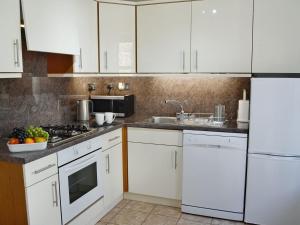 a kitchen with white cabinets and a sink at Summerlea Cottage in Moffat