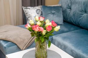 un jarrón de flores en una mesa delante de un sofá en Cozy Stay Apartment, en Kaunas