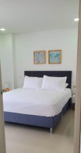 uma cama grande num quarto com duas fotografias na parede em AZ Apartments em Cartagena das Índias