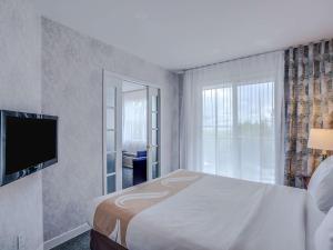 a bedroom with a bed and a large window at Hotel Quality Suites in Sainte-Anne-de-Beaupré