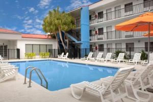 a pool with chairs and umbrellas in front of a hotel at Quality Inn Atlantic Beach-Mayo Clinic Jax Area in Atlantic Beach