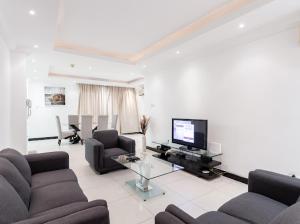 sala de estar con sofás y TV de pantalla plana. en Unit 5, Capella Place, en Accra