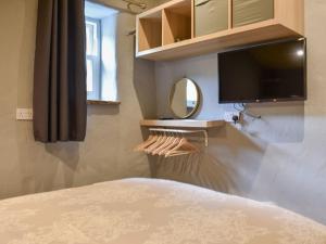 een slaapkamer met een bed en een televisie en een spiegel bij Doddick Beck - Uk39153 in Threlkeld