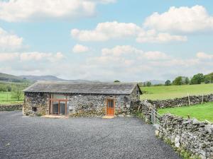 a stone cottage in a field with a stone wall at Doddick Beck - Uk39153 in Threlkeld