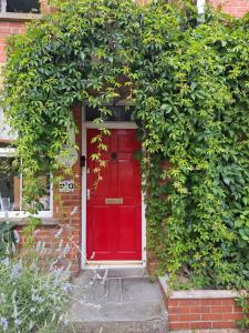 a red door in a brick building with green leaves at Pilgrims of the Goddess in Glastonbury