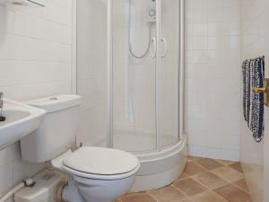 a white bathroom with a toilet and a shower at Oakleigh By The Sea in Cromer